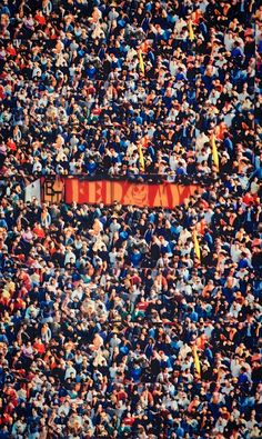 a large group of people standing in the middle of a stadium with a red banner