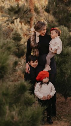 a woman and two children are standing in the woods