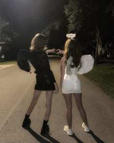 two women dressed in costumes are walking down the street at night with their arms around each other