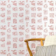 a wooden chair sitting in front of a wall with red and white designs on it