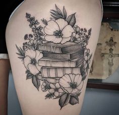 a woman's thigh with books and flowers on it