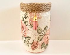 a jar that has some flowers on it and a gold charm hanging from the top