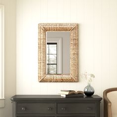 a room with a dresser, mirror and vase on the table in front of it