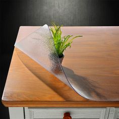 a wooden table topped with a plant on top of a glass cutting board next to a knife