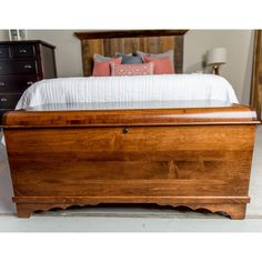 a large wooden bed with white sheets and pillows