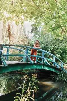 a woman is standing on a bridge over water