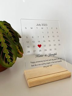 a wooden stand with a calendar on it and a potted plant behind the table