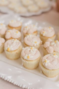 cupcakes with white frosting and yellow sprinkles on a plate