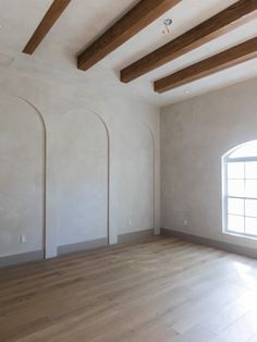 an empty room with white walls and wood beams on the ceiling is seen in this image