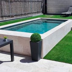 a small rectangular pool in the middle of a lawn with chairs and tables around it