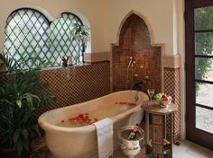 a bathroom with a large tub next to a window and potted plant in the corner