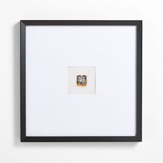 a black frame with a white wall and two pictures on the wall, one has a small window in it