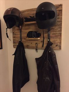 a helmet and gloves are hanging on the wall next to a coat rack with two coats