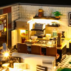 a lego model of a kitchen and dining area with lights on the counter, chairs and table