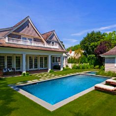 a house with a swimming pool in the middle of it and two lawn chairs next to it