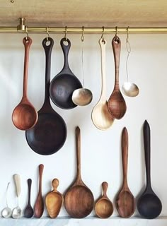 several wooden spoons hanging from hooks on a wall