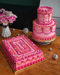 a pink cake sitting on top of a table next to a vase filled with flowers