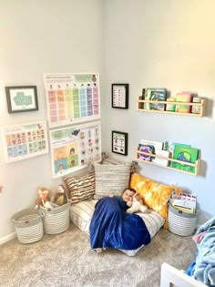 a child is sleeping on a couch in the corner of a room with many pictures