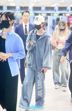 people wearing face masks in an airport terminal, some are walking and others are looking at their cell phones