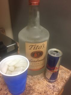 a bottle of gin and some ice cubes on a counter next to a can of soda