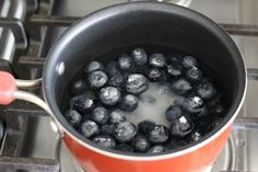 blueberries are boiling in a pot on the stove