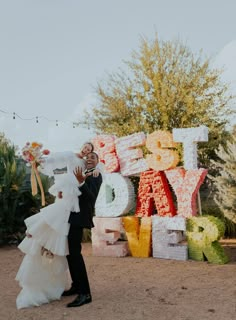 a bride and groom standing in front of the letters that spell out their love for each other