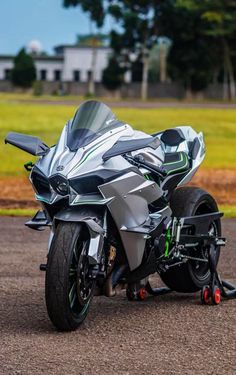 a silver and black motorcycle parked on top of a parking lot next to a field