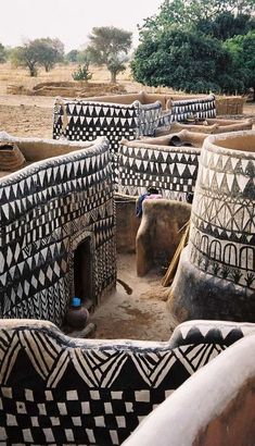 an african village with black and white designs on the walls, mud huts and trees in the background