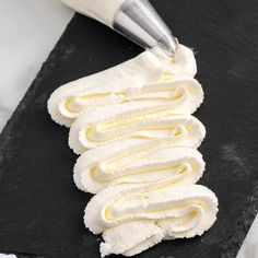 a knife is cutting into some food on a black slate board with white icing