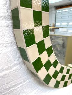 a green and white checkerboard mirror hanging on a wall next to a counter