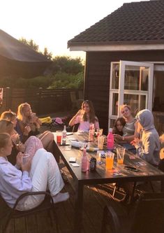 a group of people sitting around a table eating food and drinking beverages on a deck