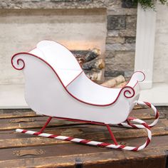 a white sleigh sitting on top of a wooden table next to a fireplace