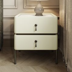 a white lamp sitting on top of a table next to a dresser with two drawers