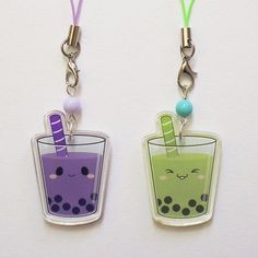 two key chains that have different colored drinks in them with faces drawn on the sides