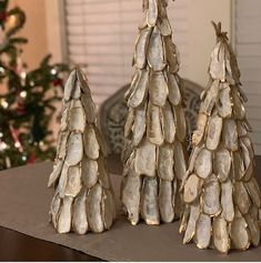 three small trees made out of seashells on a table next to a christmas tree