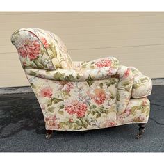 a chair with floral fabric on it sitting in front of a garage door and wall