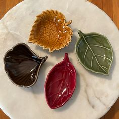 four ceramic leaf shaped dishes on a white plate