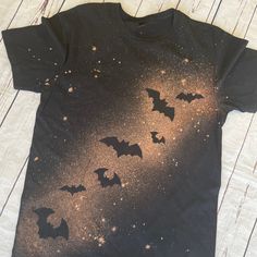 a black t - shirt with bats flying in the sky and stars all over it