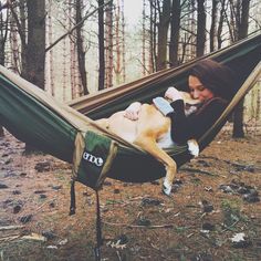 a woman laying in a hammock with her dog