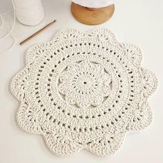 a crocheted doily sits on a table next to some yarn and scissors