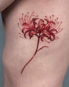 a red flower tattoo on the side of a woman's thigh, with her left leg showing