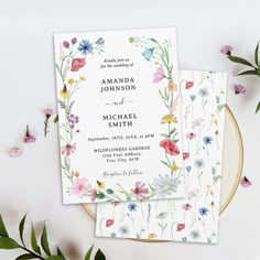 the wedding stationery is decorated with colorful flowers and greenery, along with matching envelopes