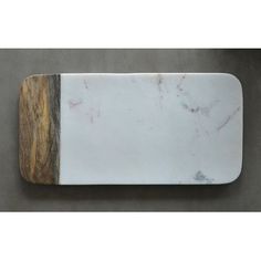 a marble and wood cutting board sitting on top of a gray surface with a wooden edge