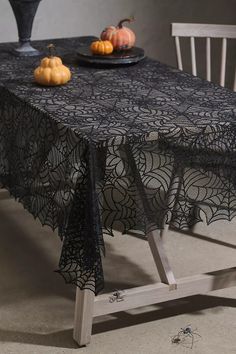 the table is covered with black lace and has pumpkins on it, along with an empty plate