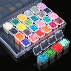 several different colors of beads in a plastic container on a black surface with other containers