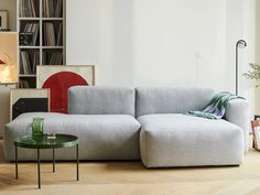 a white couch sitting next to a green table in a living room on top of a hard wood floor