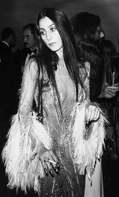 a black and white photo of a woman in a feathered dress at an event