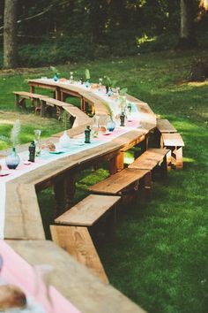 a long wooden table is set up for a picnic party with plates and glasses on it