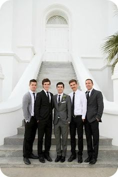 a group of men standing next to each other in front of a white building with stairs