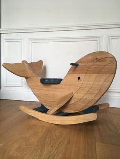 a wooden rocking whale toy sitting on top of a hard wood floor next to a white wall